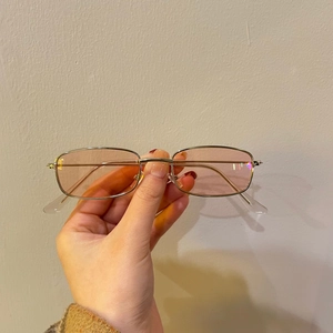 Detailed close-up of a silver thin-frame metal sunglasses with light pink lenses