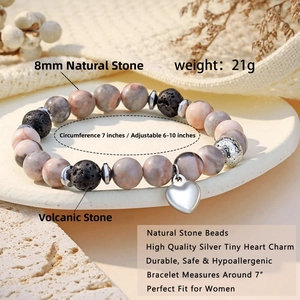 Detailed shot of 8mm natural stone and lava bead bracelet with silver heart charm on a tray