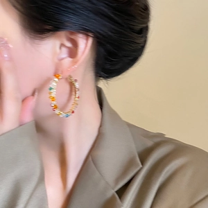 Close-up of colorful crystal hoop earrings worn by a model in a minimalist style