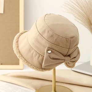 Detail of khaki bucket hat featuring a large bow and soft cream faux fur trim edge