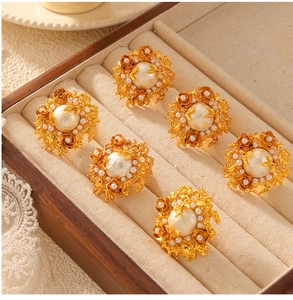 Detailed macro view of gold baroque pearl floral earrings in a velvet wooden jewelry box