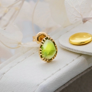 Macro shot of 14k gold plated sterling silver stud earring with pear cut green gemstone