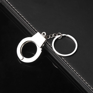 Close-up of a silver metal handcuff keychain with a polished finish on black leather