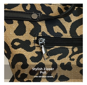 Detailed close-up of leopard print canvas fabric with metallic zipper and stylish puller
