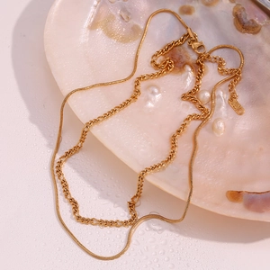 Close-up of double-layer gold snake and figaro chains resting in a pearl shell