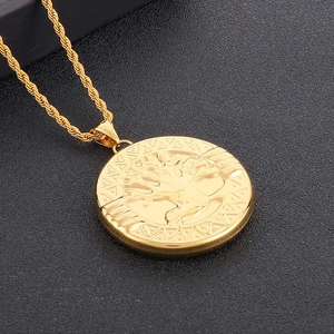 Macro shot of gold tree of life pendant on a twisted rope chain over black texture
