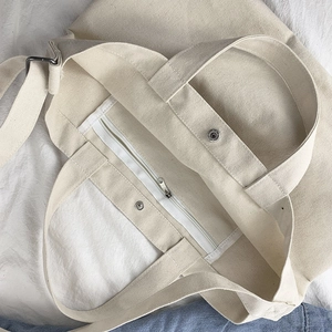 Canvas crossbody bag in cream white showing internal pocket and magnetic button closure