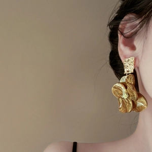 Close-up of vintage flower earrings with amber resin petals and gold textured metal details