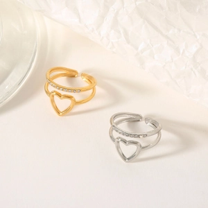 Detail of gold and silver double-layer rings with hollow heart and zircon accents
