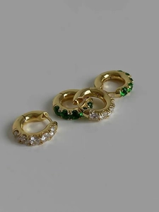 Close-up of gold-plated hoop earrings featuring green and clear zircon stones