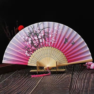 Detail of pink gradient bamboo folding fan with floral patterns and pink tassel