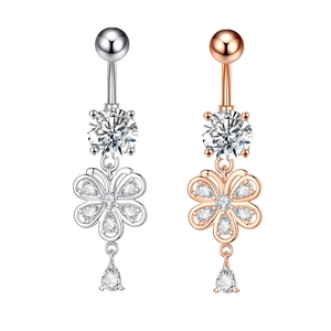 Detail of silver and rose gold belly rings with floral zircon and teardrop pendants