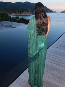 Elegant green v-neck maxi dress with fringe details and ocean pool backdrop