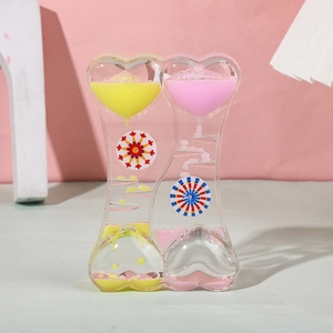 Close-up of double heart liquid motion timer with pink and yellow oil drops and rotating wheels