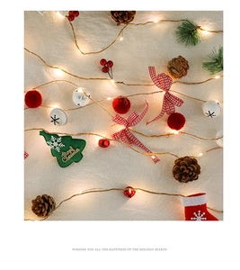Detail of Christmas string lights with pine cones, red berries, and felt tree ornaments