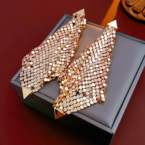 Detailed close-up of golden metal mesh drop earrings with geometric triangle accents