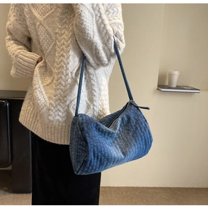 Detailed view of large blue quilted denim hobo bag worn by model in casual style