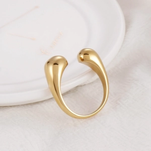 Polished gold adjustable open ring with sleek teardrop design on white ceramic