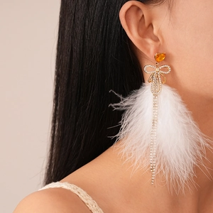 Elegant gold bow earrings with amber heart, white feathers and long sparkling tassels