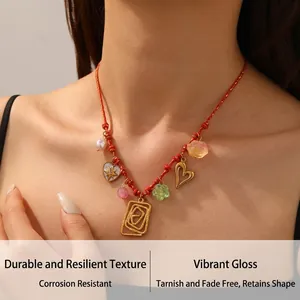Détail d'un collier en cordon rouge avec pendentifs cœurs et fleurs sur un modèle