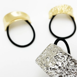 Macro detail of metallic gold and silver textured hair rings with elastic black bands