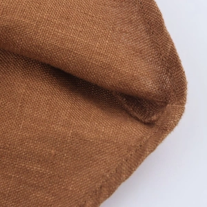 Detailed close-up of brown linen fabric texture showing durable weave on the midi skirt