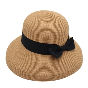 Dettaglio di un cappello da sole in paglia marrone con trama a spirale e nastro nero