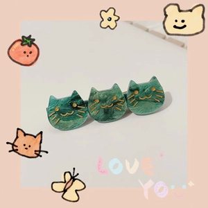 Detail of green marble acetate hair clip with three cat heads and golden whiskers