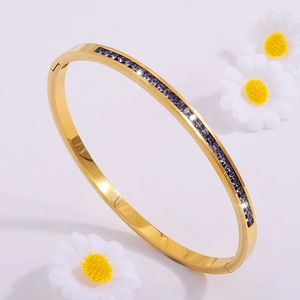 Elegante brazalete de acero de titanio dorado con circonitas moradas y flores blancas