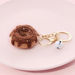 Handmade knitted donut keychain in brown and beige yarn with a small white bell and gold ring