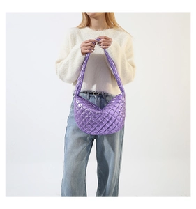 Detail of metallic purple quilted crescent bag worn by model over shoulder