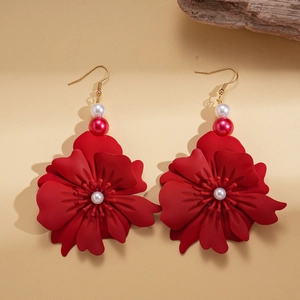 Detail of red flower earrings with gold hooks, featuring matte petals and glossy pearls