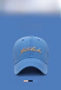 Detail of blue washed cotton baseball cap with gold Northbrook cursive embroidery