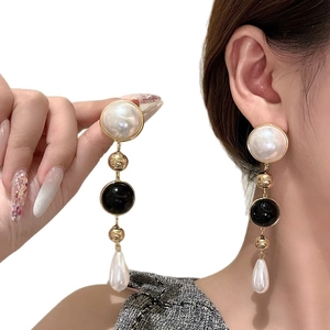 Elegant 18k gold plated drop earrings with white pearls and black beads on a female model