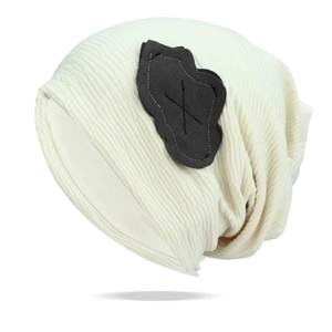 Detail of beige ribbed knit beanie featuring a grey cloud patch with cross stitching