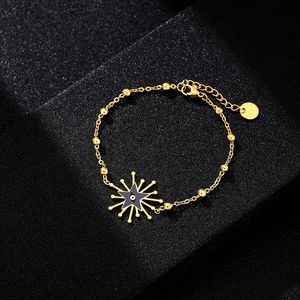 Detail of gold beaded chain bracelet featuring a blue star-shaped evil eye charm