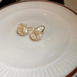 Vue rapprochée des boucles d'oreilles boules florales dorées avec pétales blancs