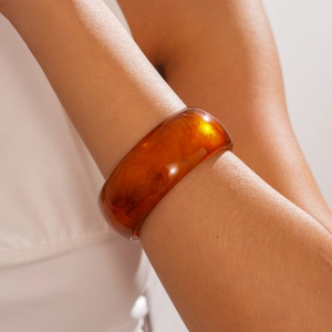 Close-up of amber resin bangle with natural texture patterns on a wrist