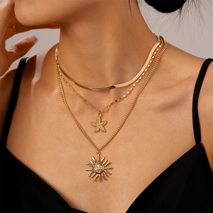 Three-layer gold metal necklace set featuring starfish and sun face pendants on a model