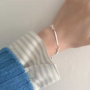 Gros plan d'un bracelet nœud en argent S925 porté au poignet sur un pull en maille bleu