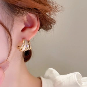 Close-up of model wearing C-shaped gold hoop earrings with white inlay and micro pavé cz