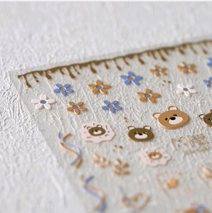 Macro detail of 3D embossed nail art stickers with bears, flowers and golden textures
