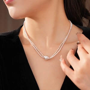 Detail of silver double-layer beaded necklace with round pearl pendant on a model