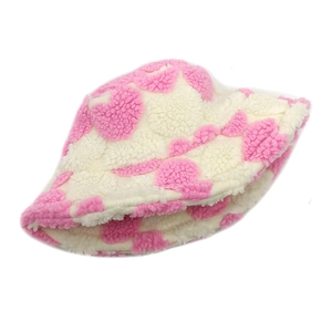 Detail view of plush sherpa bucket hat with pink jacquard heart pattern on beige fabric