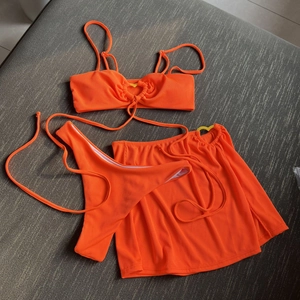Neon orange ribbed three-piece bikini set with high-cut bottom and matching beach skirt