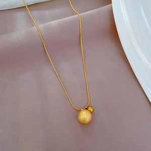 Gold titanium snake chain necklace with dual globes on purple silk and white plate