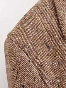 Détail d'un blazer en tweed marron à chevrons montrant l'épaule et la texture du revers