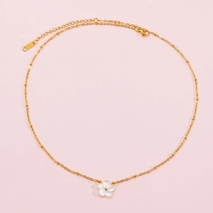 Elegant gold stainless steel necklace with a white shell flower pendant on pink background
