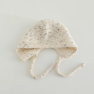 Détail de la texture en maille côtelée et du fil moucheté sur le bonnet bébé à oreillettes