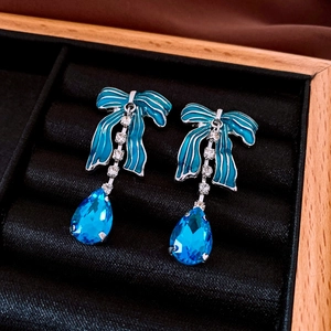Detailed close-up of blue bow earrings with crystals in a black velvet jewelry box